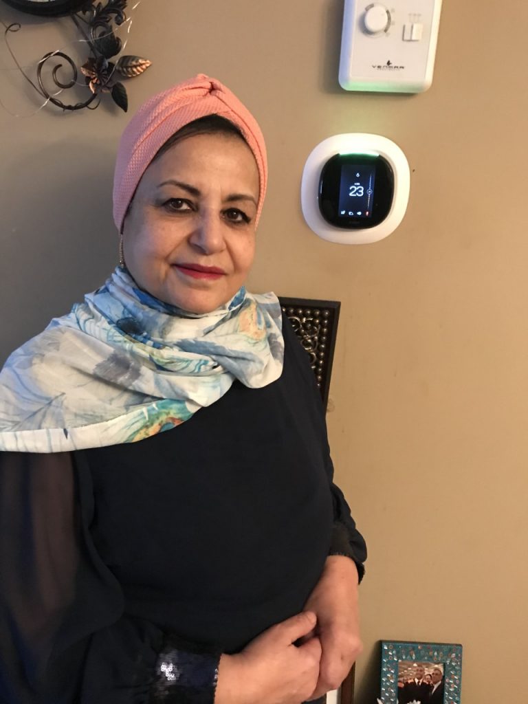 Tahani standing next to her Alexa Thermostat