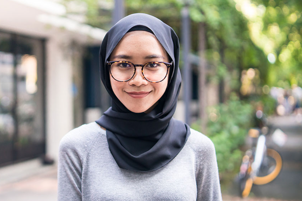 A photo of a woman wearing a hijab outside in the park.