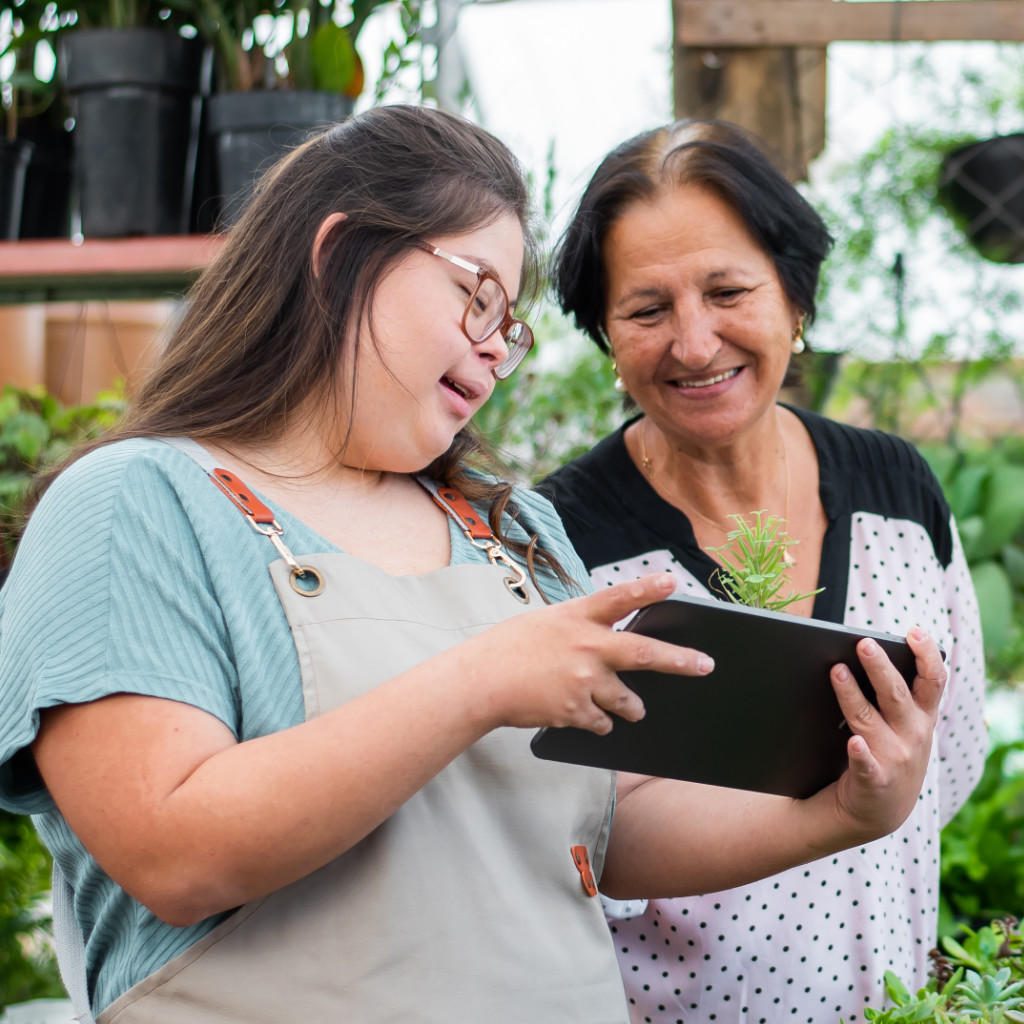 A photo of two greenhouse employees looking at information on a tablet.