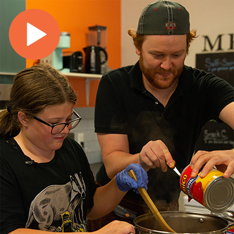 A photo of Joey cooking with his students.