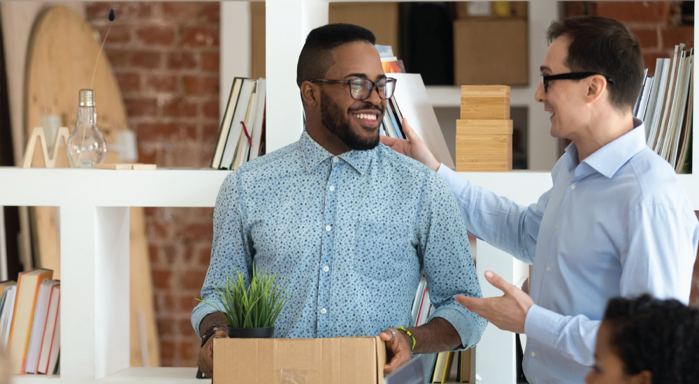 A photo of two people moving items into a home.
