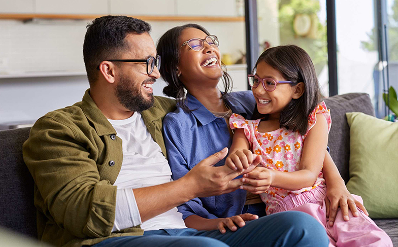 A photo of a family sitting on the couch together.