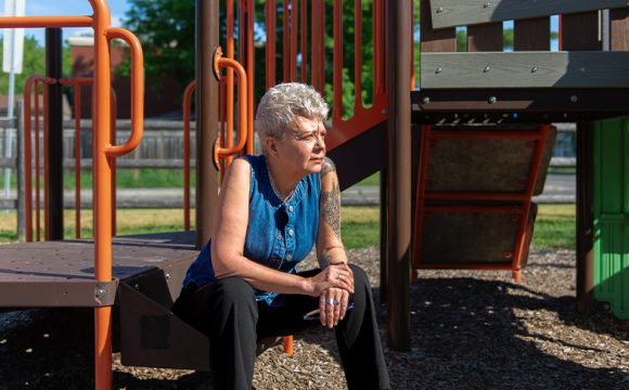 A photo of Heather sitting on a play structure.